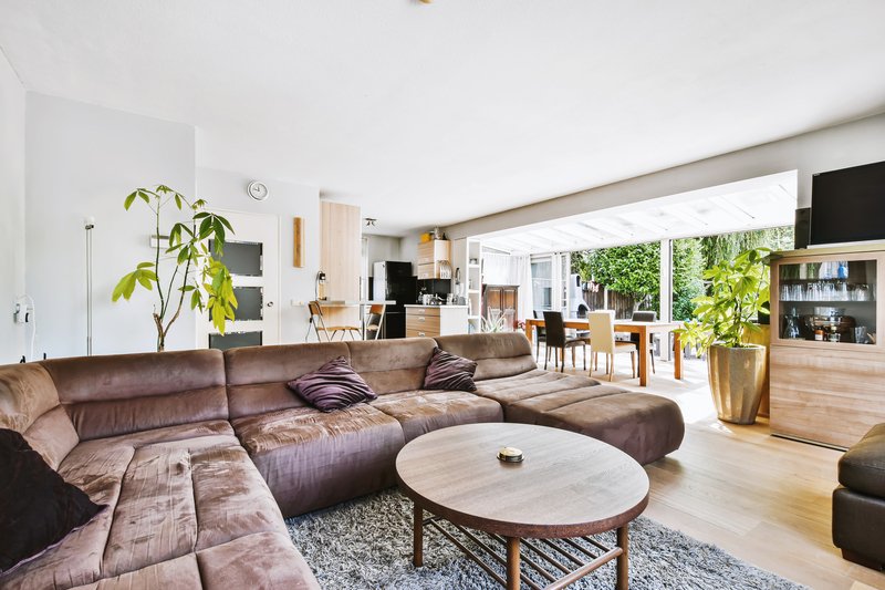 Sala amplia con sillones en color café y paredes blancas de una casa grande